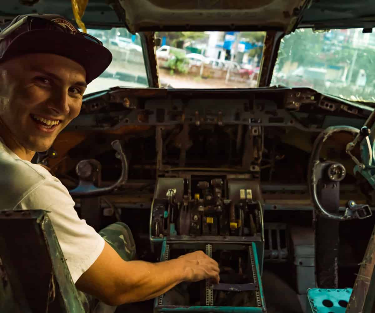 My mate sits in the scavenged Boeing 747's cockpit, Bangkok's Plane Graveyard, Thailand.