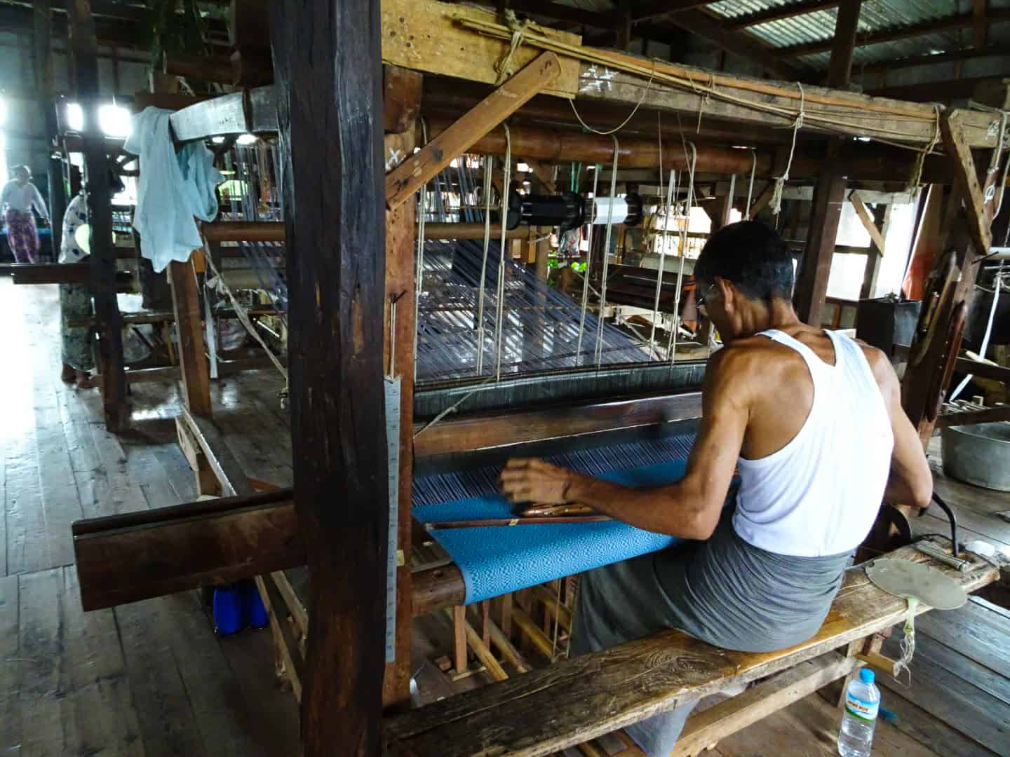 A man weaving fabric into a longjyi