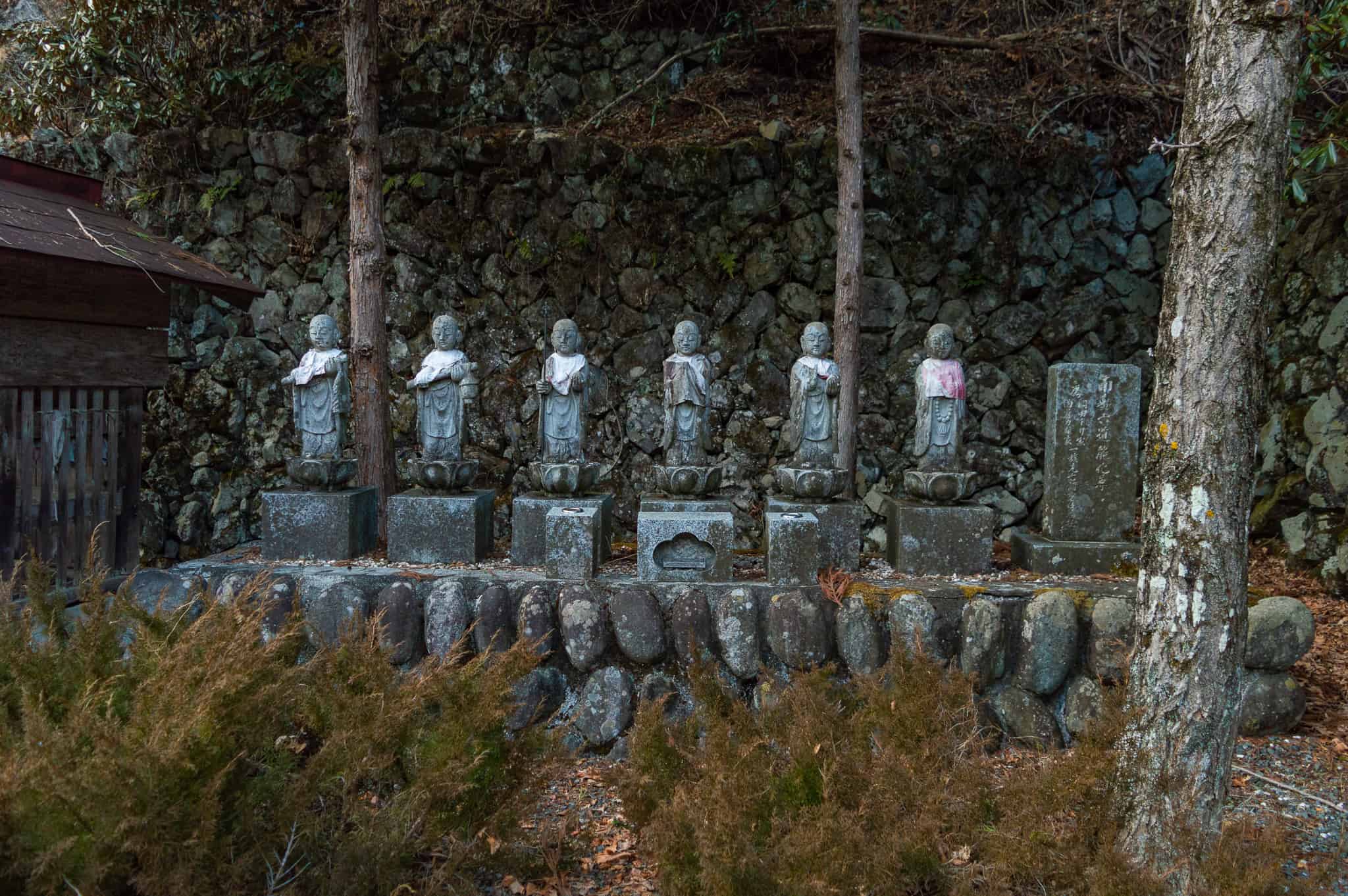 Statues lined up along a stone wall at Taiyoji Temple, Japan