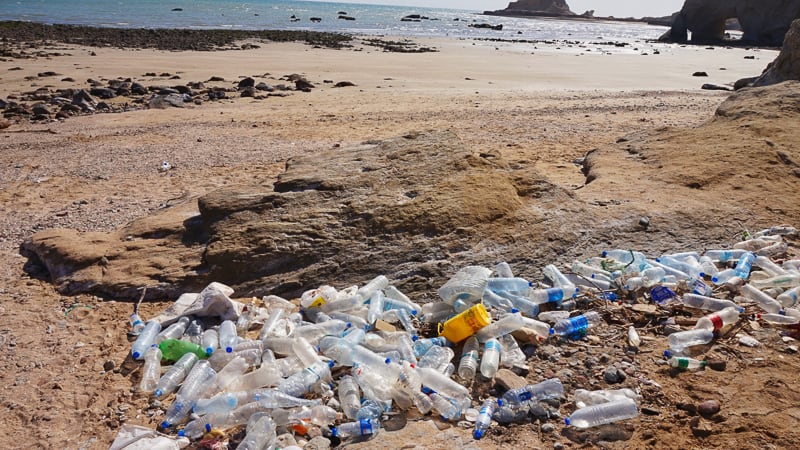 Plastic bottles spread along a beautiful sandy beach 